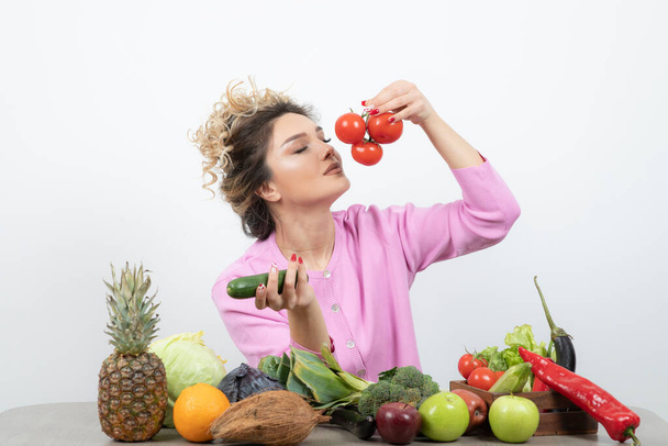 Lockige Frau sitzt am Tisch mit viel frischem Gemüse - Foto, Bild