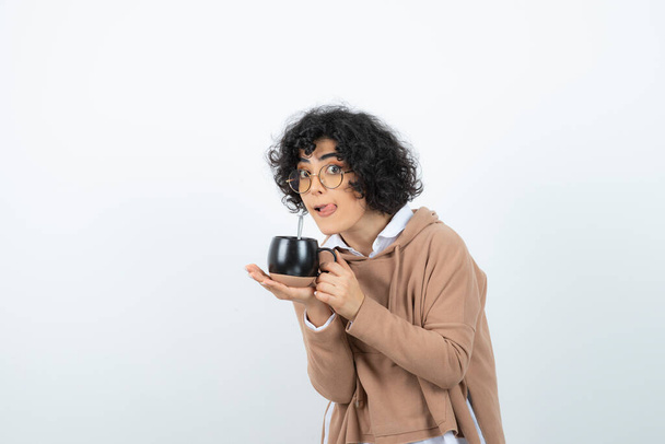 Portrait of curly woman in glasses holding cup of coffee. High quality photo - Foto, Imagem