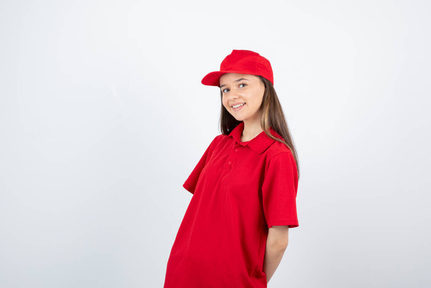Photo of young female courier in red uniform feeling happy. High quality photo - Photo, Image