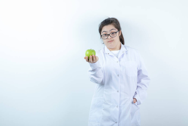 Young female girl in doctor's uniform holding green apple . High quality photo - Photo, image