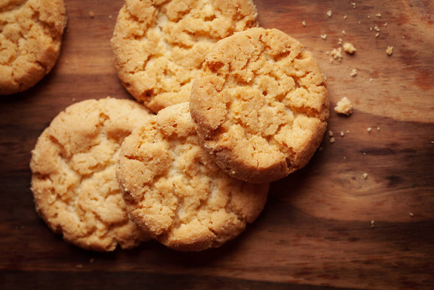 Close-up of delicious freshly baked simple cookies or biscuits. Isolated over a wooden top  background. - Photo, Image
