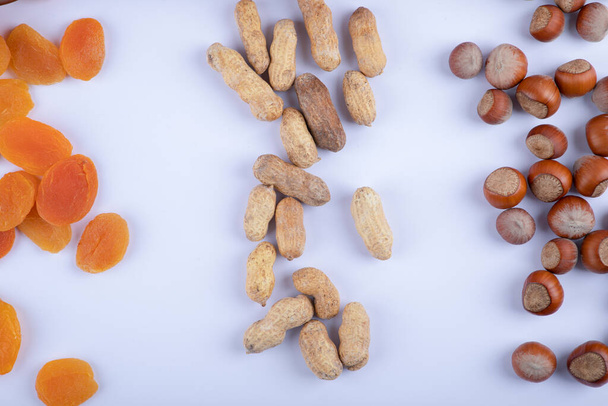 Dried organic apricots, peanuts and hazelnuts on white background. High quality photo - Fotografie, Obrázek