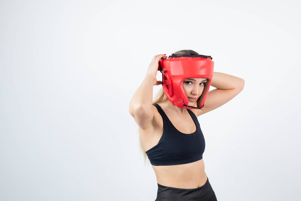 Young blonde woman in crop top wearing red boxing helmet. High quality photo - Foto, Bild