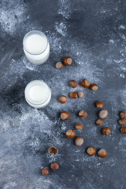 Skleněné šálky čerstvého mléka se zdravými makadamovými ořechy na mramorovém stole. Kvalitní fotografie - Fotografie, Obrázek