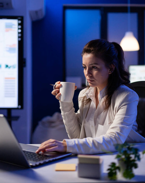 Freelancer woman with a cup of coffee tapping on business computer - Foto, Imagem