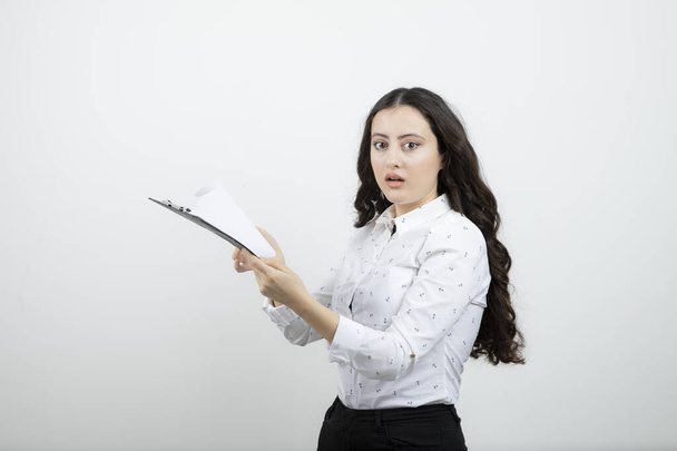 Successful business woman holding clipboard against white wall . High quality photo - Φωτογραφία, εικόνα