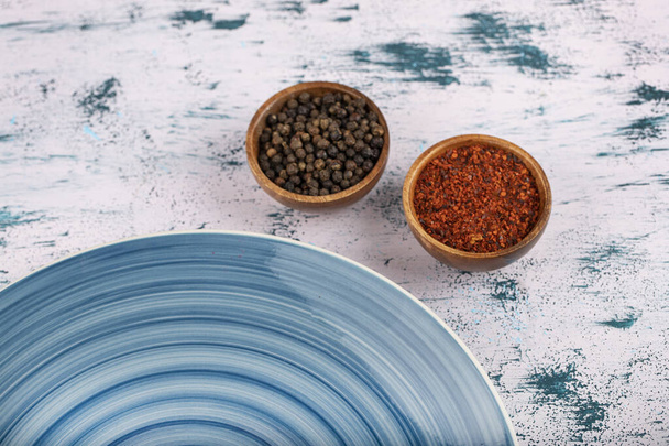Grani di pepe con polvere e piatto blu posto sul tavolo di pietra. Foto di alta qualità - Foto, immagini