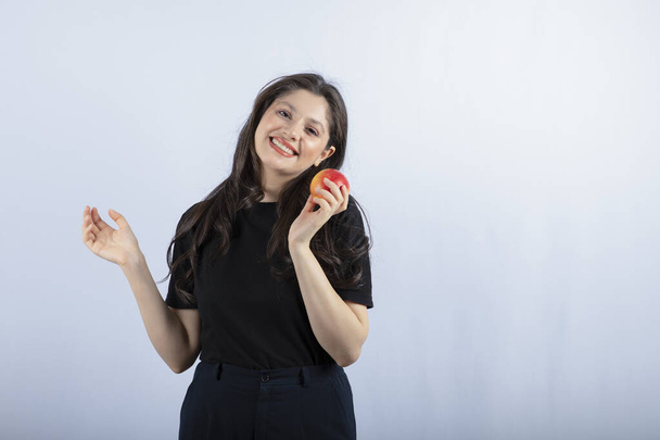 Фото красивої молодої жінки в чорному верху, що тримає свіже яблуко. Високоякісна фотографія
 - Фото, зображення