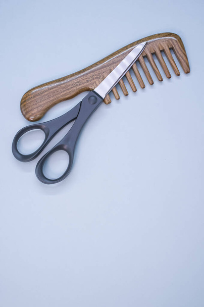 A closeup shot of scissors and hair comb on a blue surface - copy space - Foto, immagini