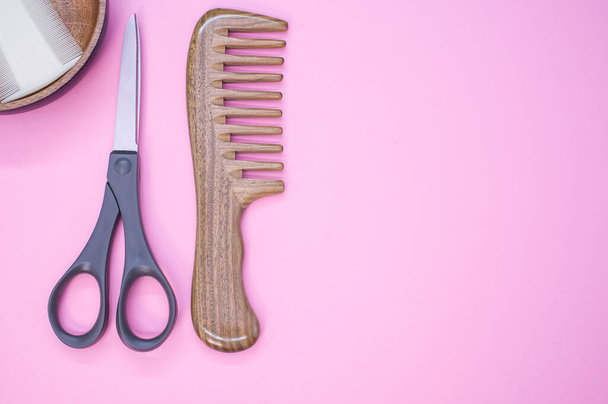 Uma vista superior de escovas de cabelo e tesoura em um fundo rosa - Foto, Imagem