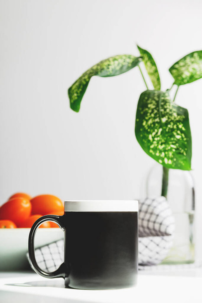 Schwarze Kaffeetassen-Attrappe auf dem Küchentisch. Cup-Attrappe für Design  - Foto, Bild