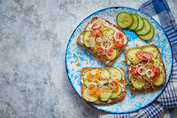 Plate with toasts with cucomber, tomatoes and crumbled feta and radish sprouts - Foto, Imagem