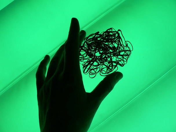 Egy kéz, ami egy halom absztrakt fémszalagot tart - Fotó, kép
