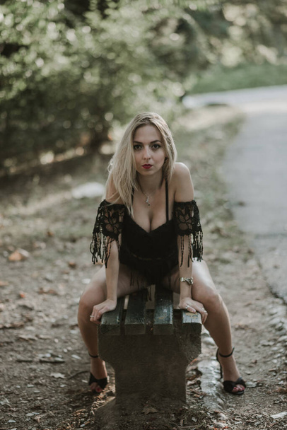 A sexy blonde female posing on a wooden bench in a park - Foto, Bild