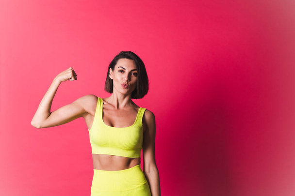 Hermosa mujer en forma de amarillo brillante ajuste ropa deportiva sobre fondo rosa feliz movimiento excitado cuerpo perfecto fitness motivación - Foto, imagen
