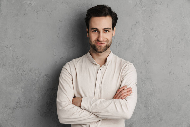 Joyful handsome guy smiling and looking at camera isolated over grey wall - Foto, Bild