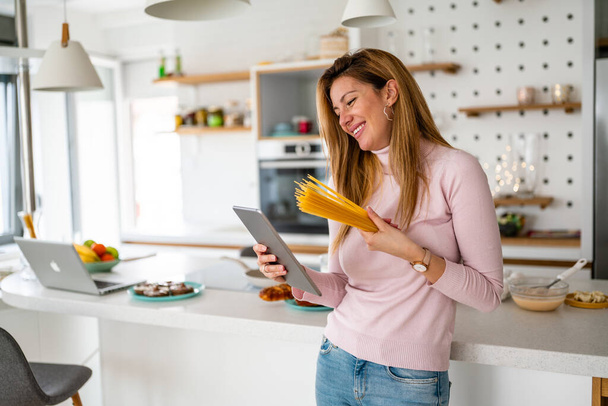 Портрет красивой счастливой женщины с макаронами на кухне, готовящейся к приготовлению - Фото, изображение