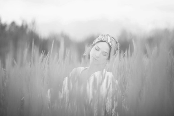 монохромный снимок красивой женщины, прогуливающейся в поле днем, романтическое настроение - Фото, изображение