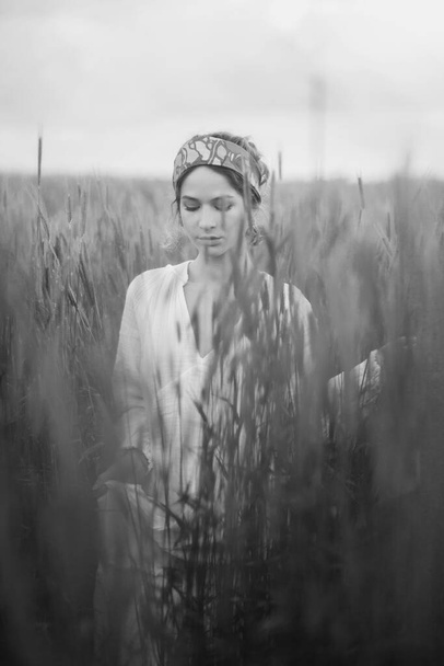 монохромный снимок красивой женщины, прогуливающейся в поле днем, романтическое настроение - Фото, изображение