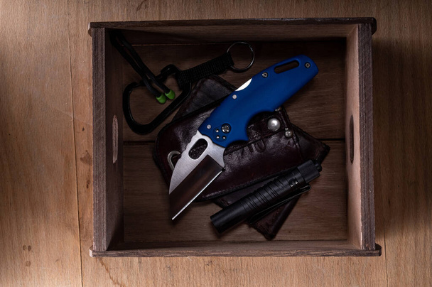 Taschenmesser und andere Alltagsgegenstände. Geldbörse und Messer in einer Schachtel. Karabiner und Messer. - Foto, Bild