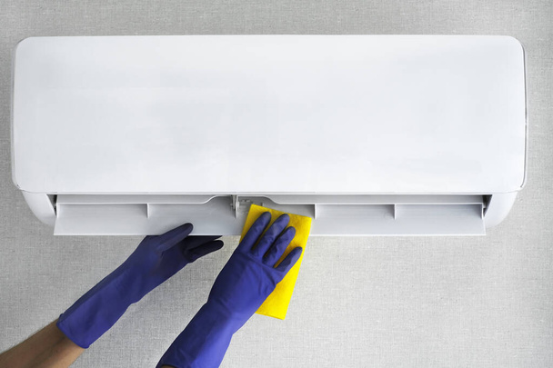 a man to clean the air conditioner at home with gloves with a special tool. cleaning company for cleaning. air conditioner cleaning mockup - Φωτογραφία, εικόνα