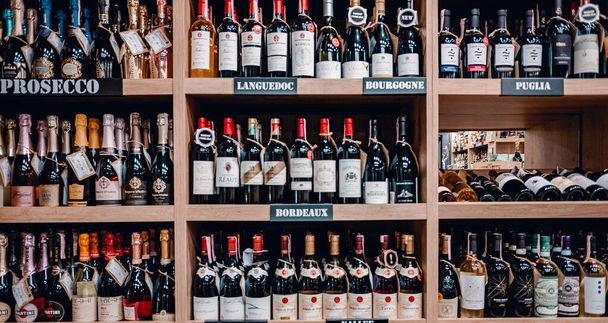 Minsk, Belarus - Juny 27, 2021: Various wine bottles sale on the wooden shelf in a supermarket shop. - Fotó, kép