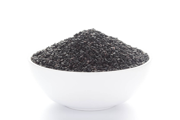 Close-up van Organic Black Sesam zaden (Sesamum indicum) of Black Til met schelp in een witte keramische schaal - Foto, afbeelding