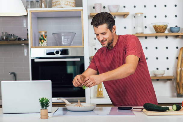 Jóképű férfi főz otthon vacsorát készít a konyhában. - Fotó, kép