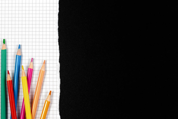 Buntstifte auf weißem, quadratisch aufgerissenem Papier über schwarzer Schultafel. Zurück zur Schule, Lernkonzept. Ansicht von oben, Kopierraum - Foto, Bild
