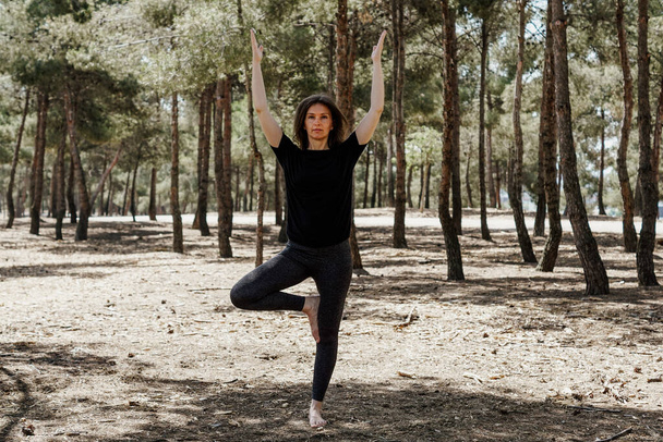 A middle-aged female in sportswear stretching in a park - Photo, image