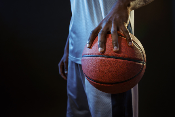 Forte mano giocatore di basket tiene palla in studio, sfondo nero. Ballerino professionista maschile in abbigliamento sportivo gioco dello sport, sportivo alto - Foto, immagini