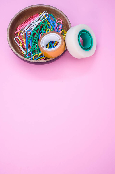 A vertical shot of multi-colored paper clips and duct tape on a pink surface - copy space - Fotoğraf, Görsel