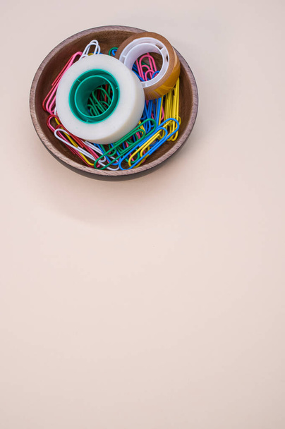 A vertical shot of multi-colored paper clips and duct tape on a beige surface - copy space - Foto, Imagem