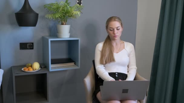 Vakava nainen käyttää kannettavaa tietokonetta kotona - Materiaali, video