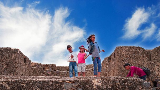 Modern davranışları olan modaya uygun çocuklar selfie çekiyorlar. Çocuklar mavi gökyüzü arka planına sahip antik bir kaleye ateş ediyorlar.. - Fotoğraf, Görsel