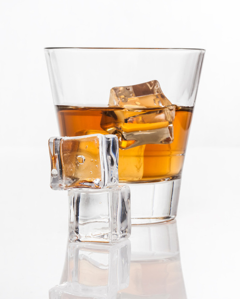 Glass of whiskey with ice, isolated on white background and small depth of field - Fotó, kép