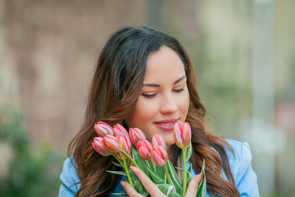 Retrato de uma bela jovem mulher em um terno azul com um buquê de tulipas. - Foto, Imagem
