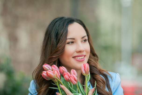 Ritratto di una bella giovane donna in abito blu con un bouquet di tulipani. - Foto, immagini