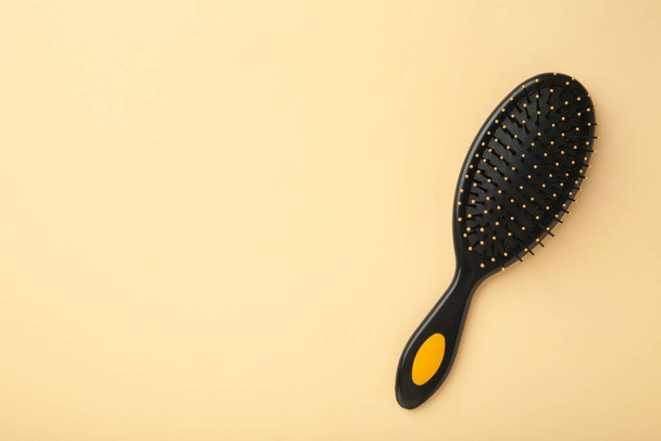 Hair brush with a black handle on beige background. Top view - 写真・画像