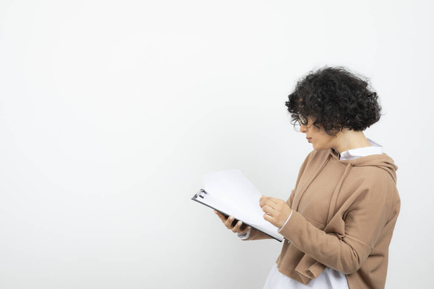 Kıvırcık saçlı, gözlüklü genç bir kadın panoda notlar okuyor. Yüksek kalite fotoğraf - Fotoğraf, Görsel