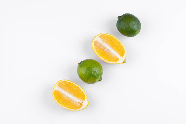 Half sliced juicy lemons and whole limes isolated on white background. High quality photo - Photo, Image
