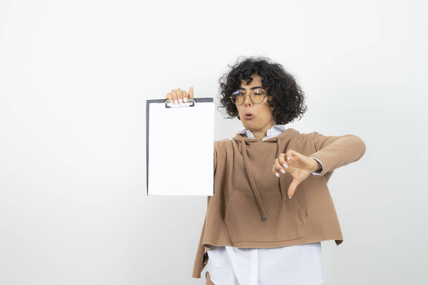 Egy fiatal nő portréja szemüvegben, üres írótáblával, hüvelykujjával lefelé. Kiváló minőségű fénykép - Fotó, kép