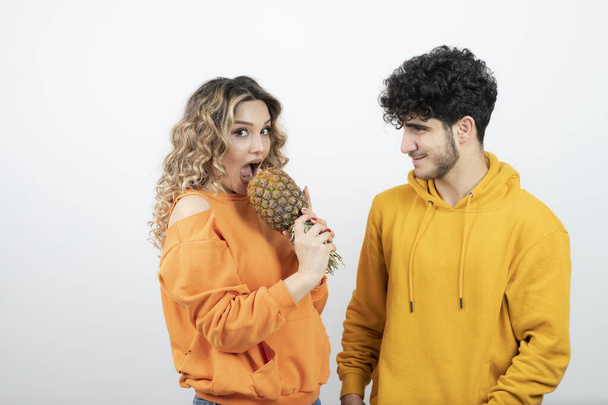 Egy fiatal nő ananásszal a barna férfi modell mellett. Kiváló minőségű fénykép - Fotó, kép
