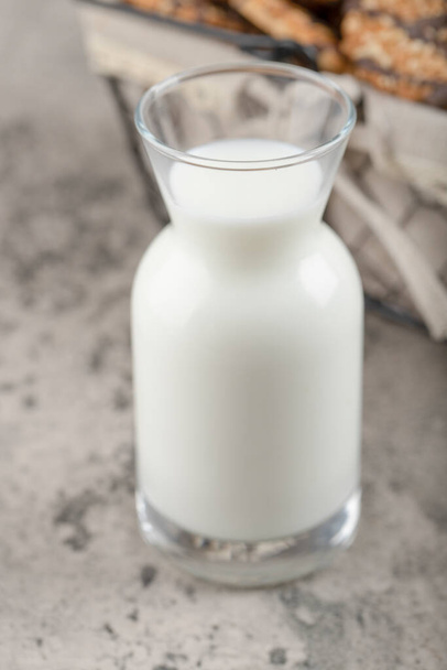 Proutěný koš ovesných sušenek se sklenicí čerstvého mléka na mramoru. Kvalitní fotografie - Fotografie, Obrázek