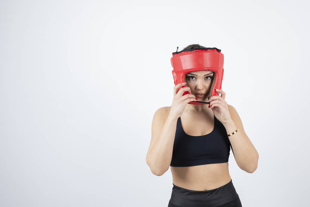 Mujer rubia joven con casco de boxeo rojo de pie y posando. Foto de alta calidad - Foto, Imagen