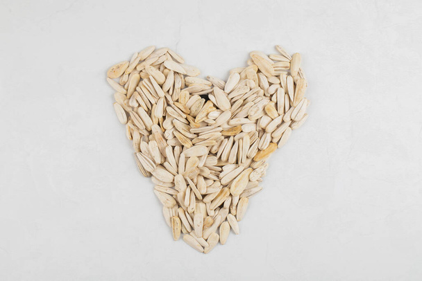 Sunflower seeds in shape of heart placed on white background . High quality photo - Foto, Imagem