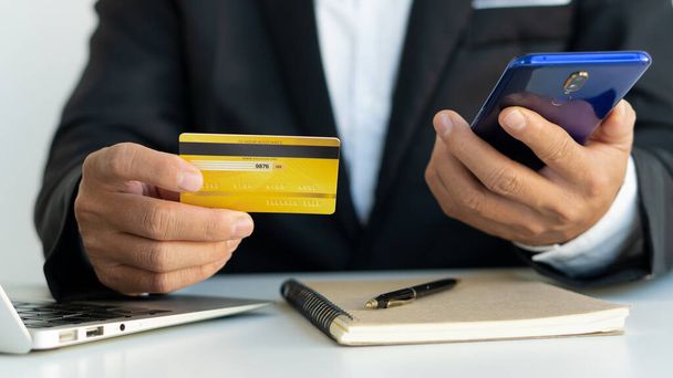 Kredi kartıyla ödemeyi ev telefonuyla, eller plastik kredi kartı tutarak ve dizüstü bilgisayar kullanarak yapıyor. Çevrimiçi alışveriş kavramı.  - Fotoğraf, Görsel