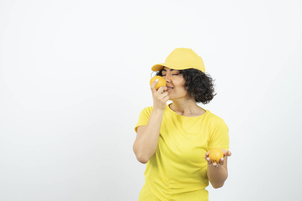 ritratto di una bella giovane donna con arance in posa su sfondo bianco   - Foto, immagini