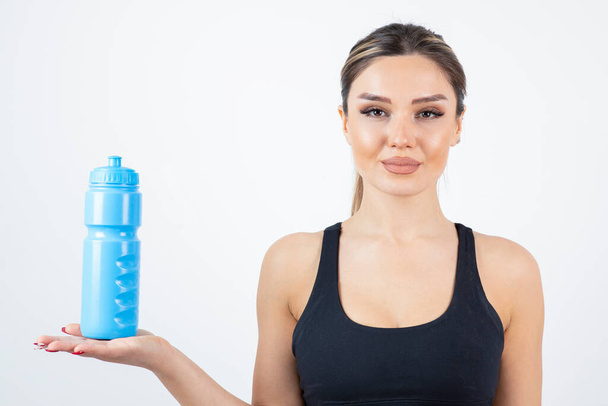Ritratto di giovane donna atletica che tiene una bottiglia d'acqua blu. Foto di alta qualità - Foto, immagini