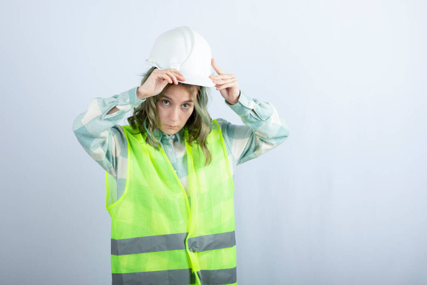 白い背景に立って緑のベストで若い建設労働者の写真。高品質の写真 - 写真・画像